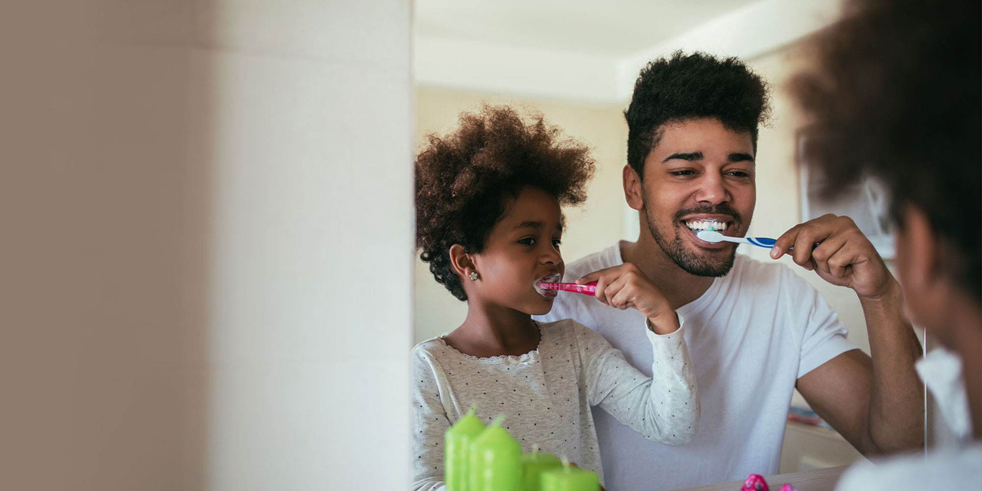 father and daughter brushing their teeth in the bathroom together