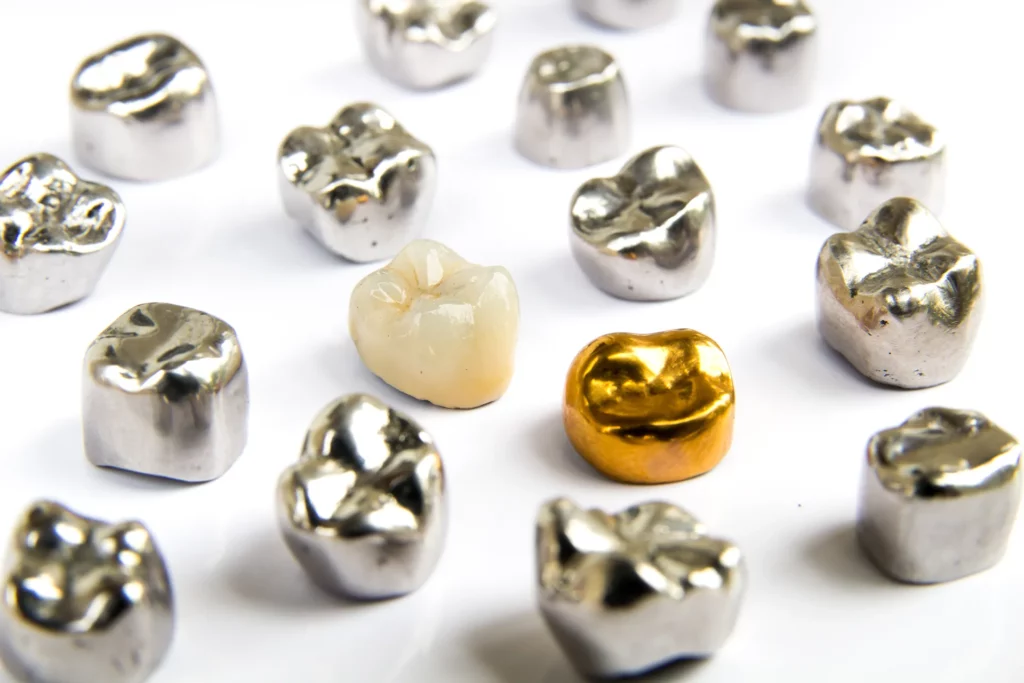 Various types of dental crowns including metal, ceramic, and gold on a white background
