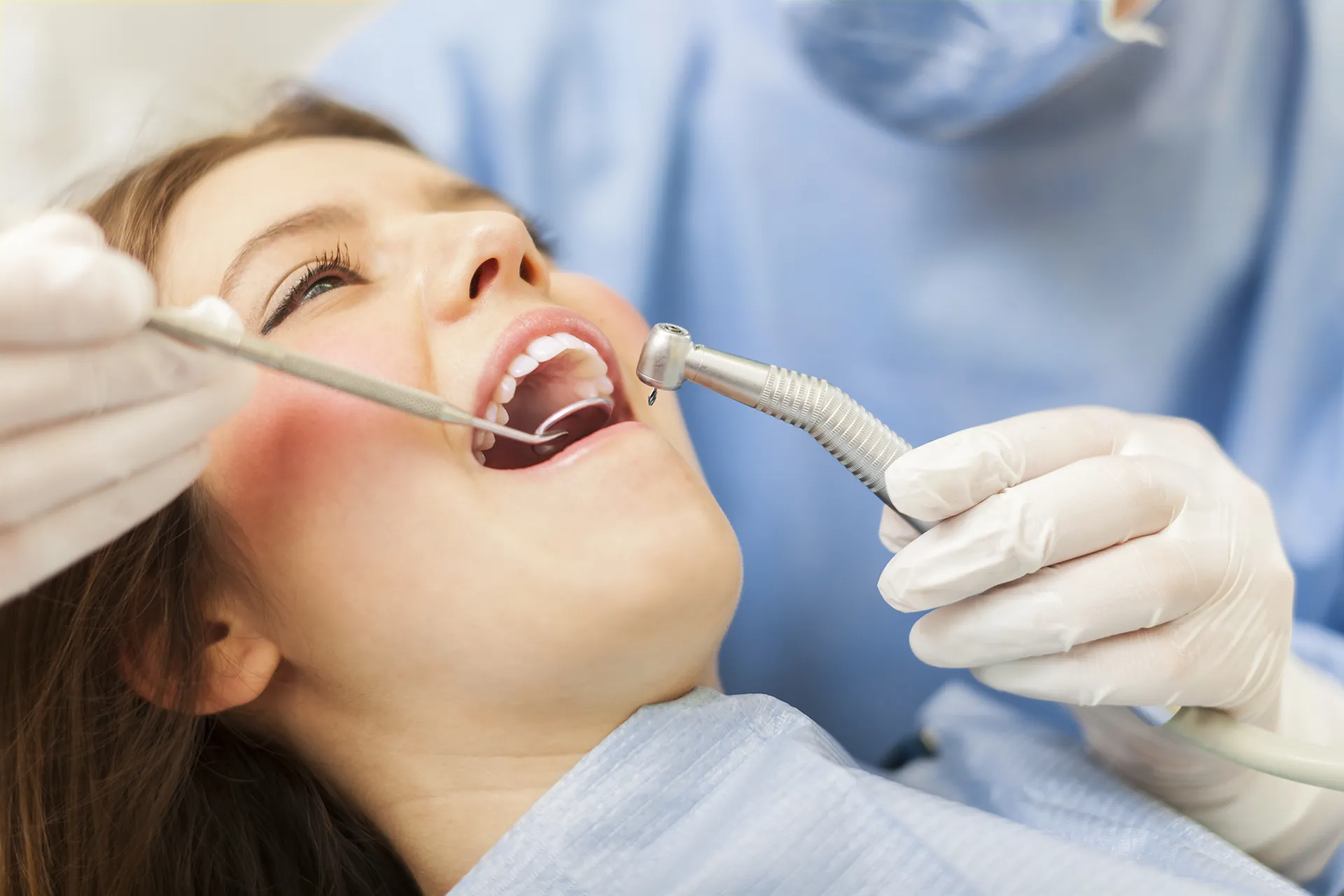 Patient undergoing dental treatment with a dentist using tools for oral care.