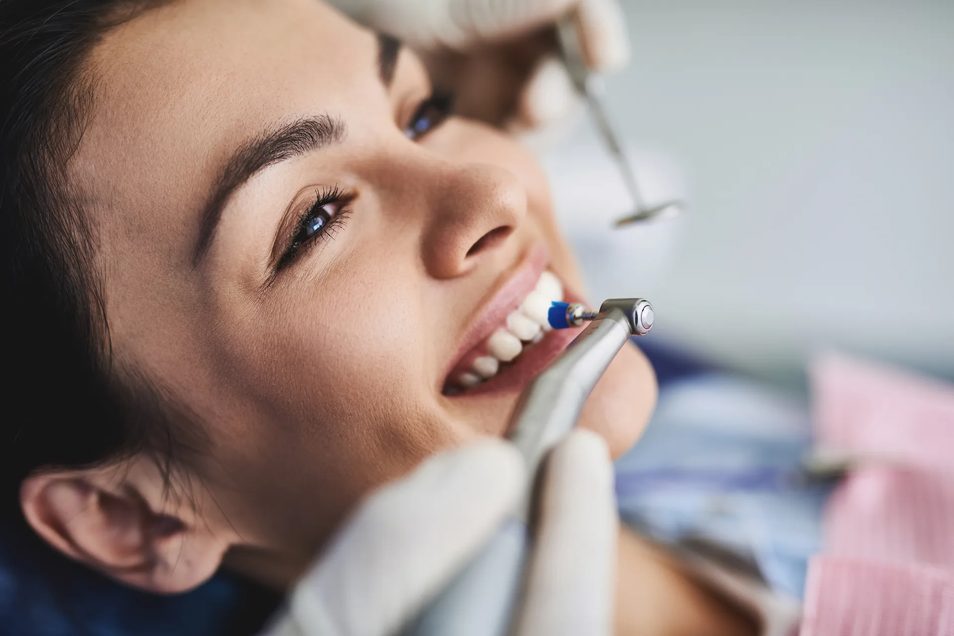 Dentist performing teeth cleaning procedure on a smiling patient