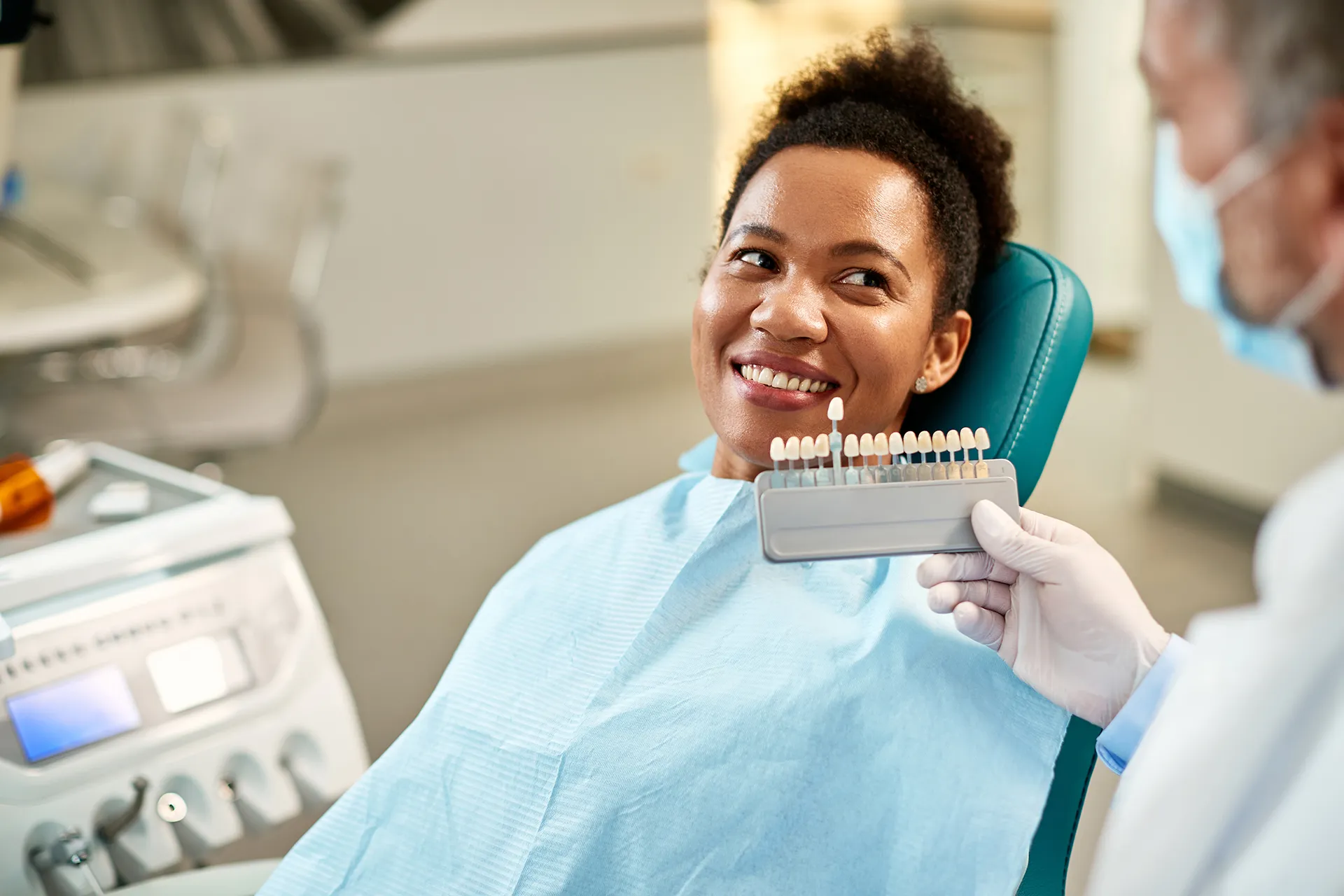 Dentist showing shade guide to patient for teeth whitening options.