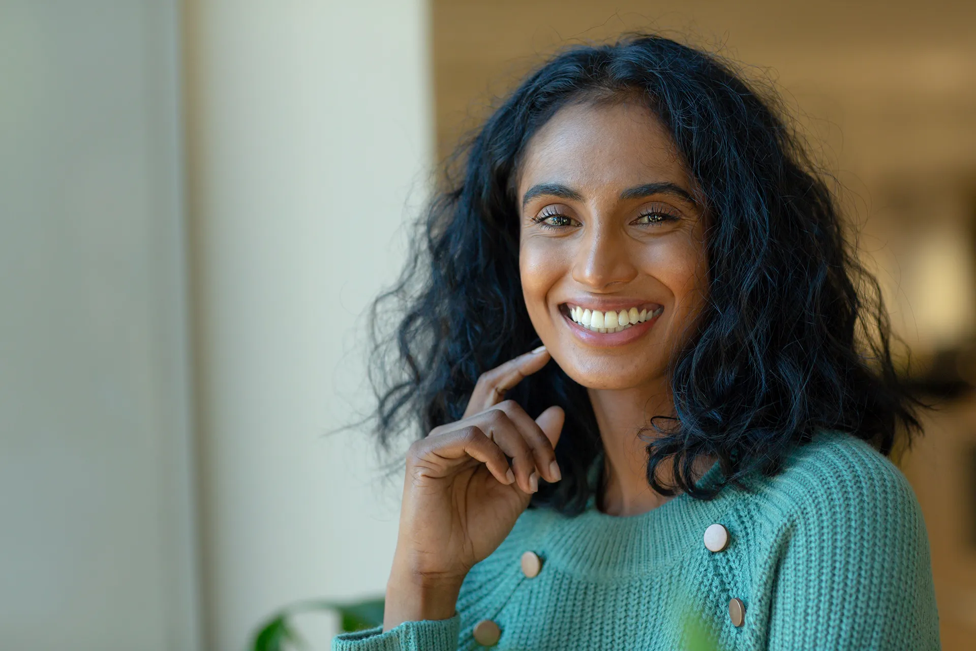 Close up of a smiling woman in green at a workplace.