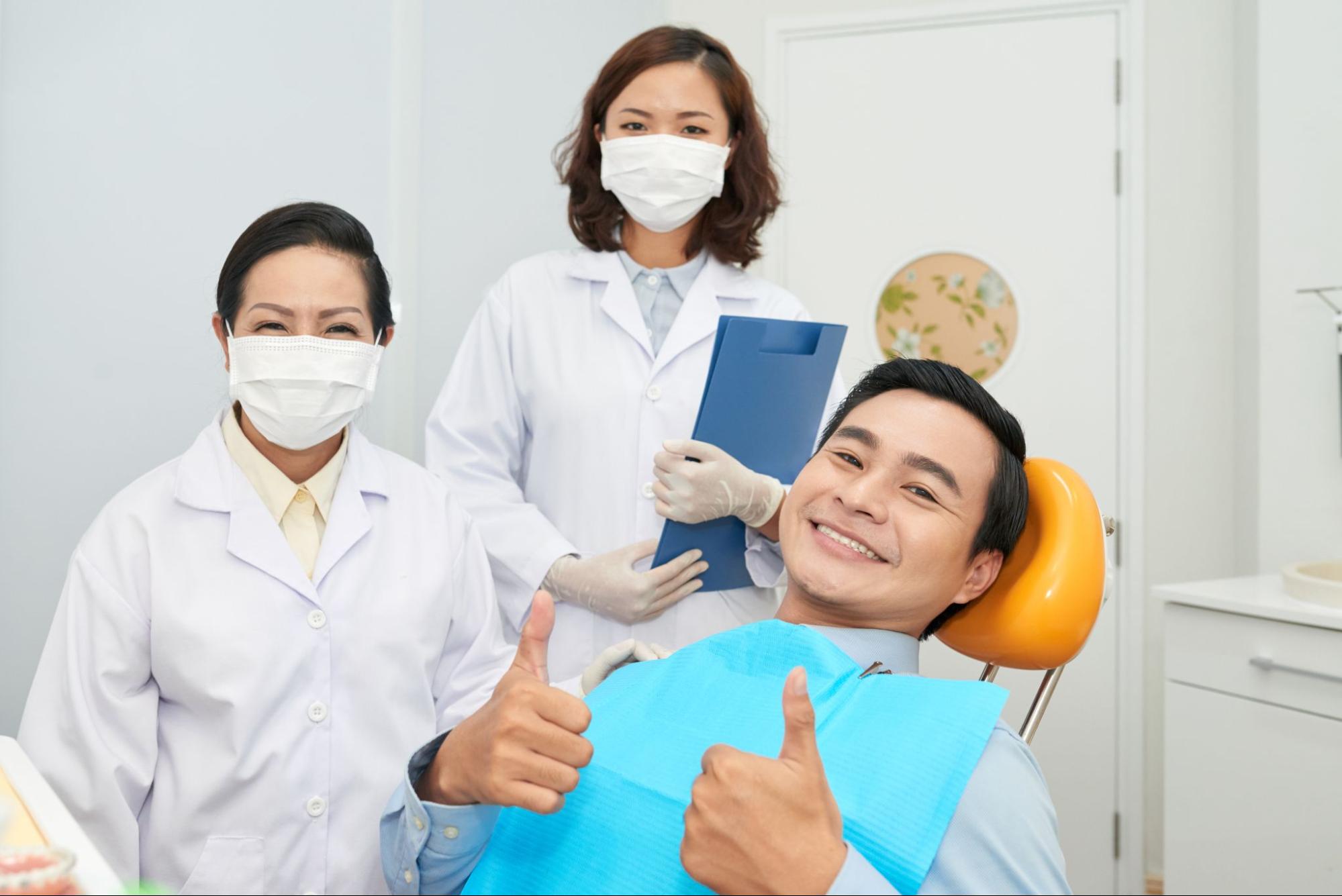 In a dental office, a man and woman express their approval by giving thumbs up, reflecting a successful dental appointment.