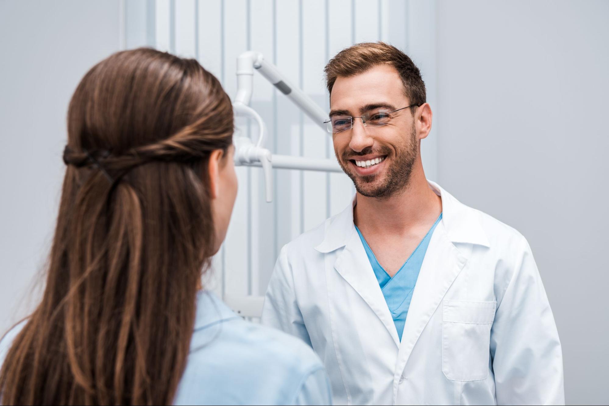 Smiling male dentist next to a female patient. 