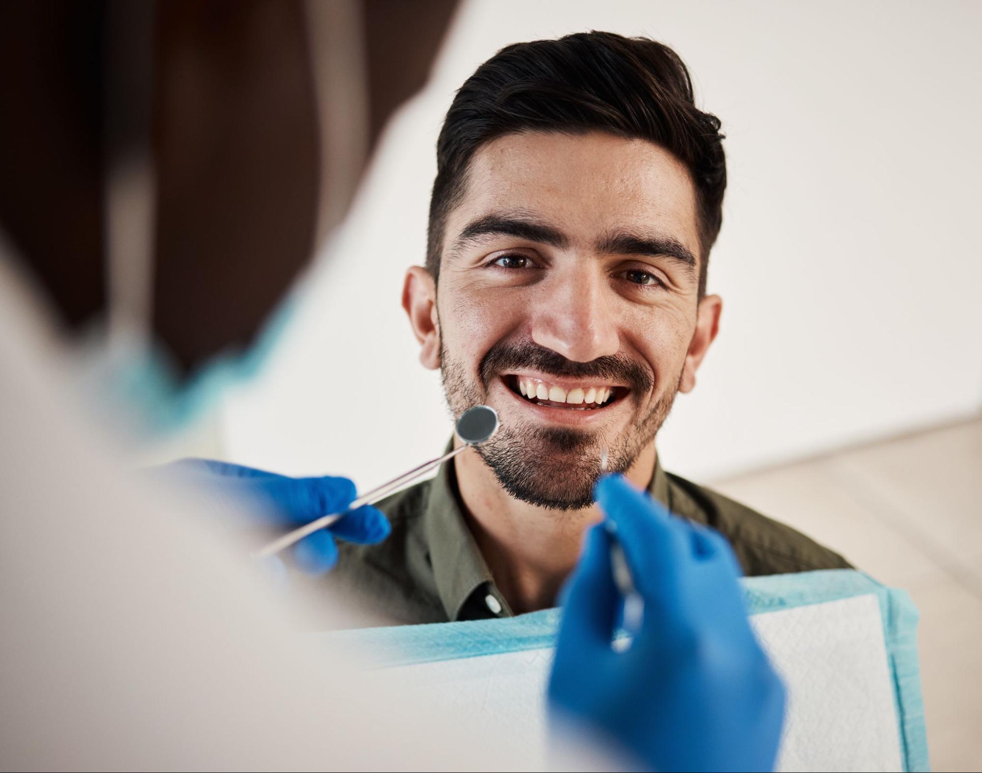 Man smiling next to a dentist. 