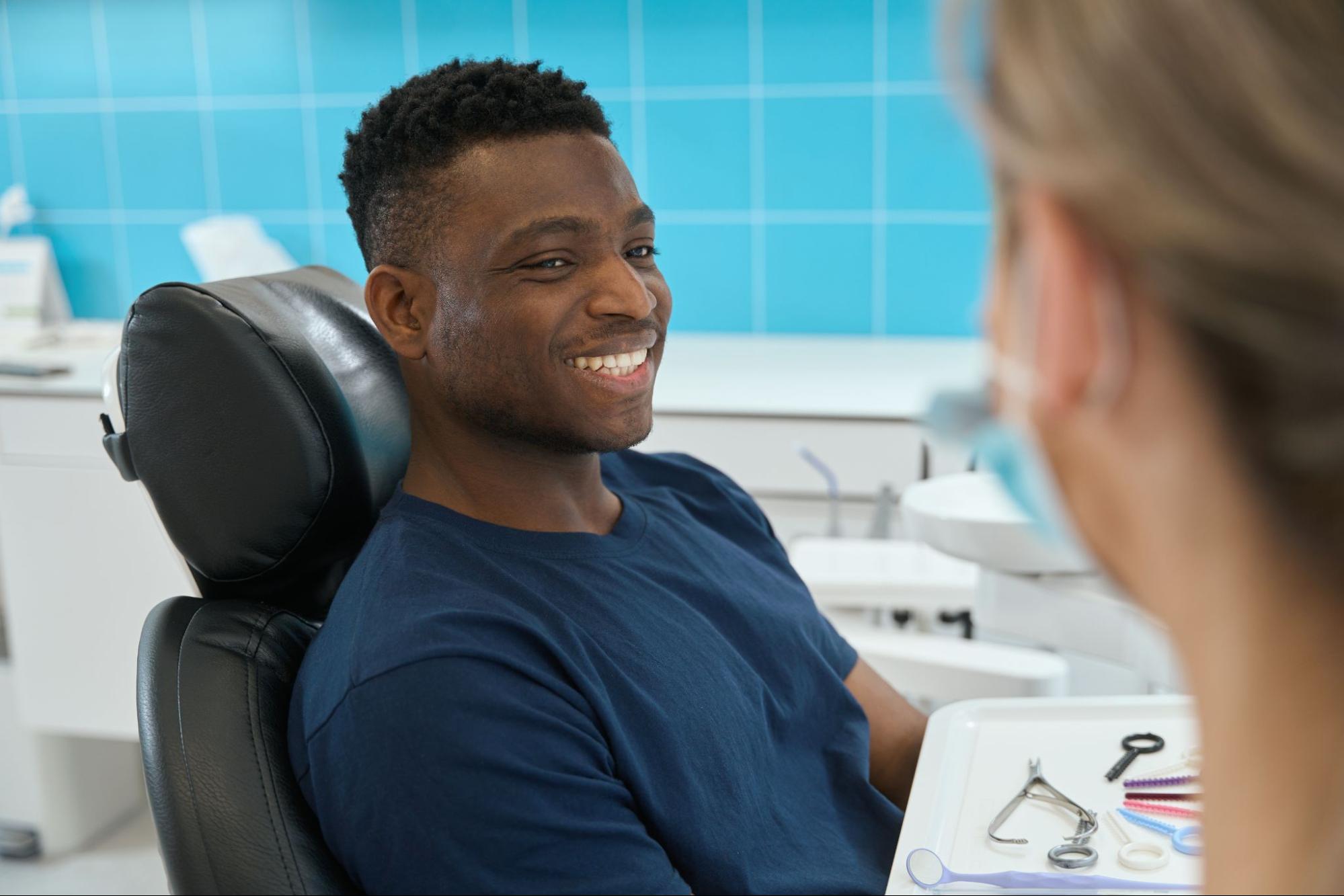 Man smiling in an exam chair next to a female hygienist.