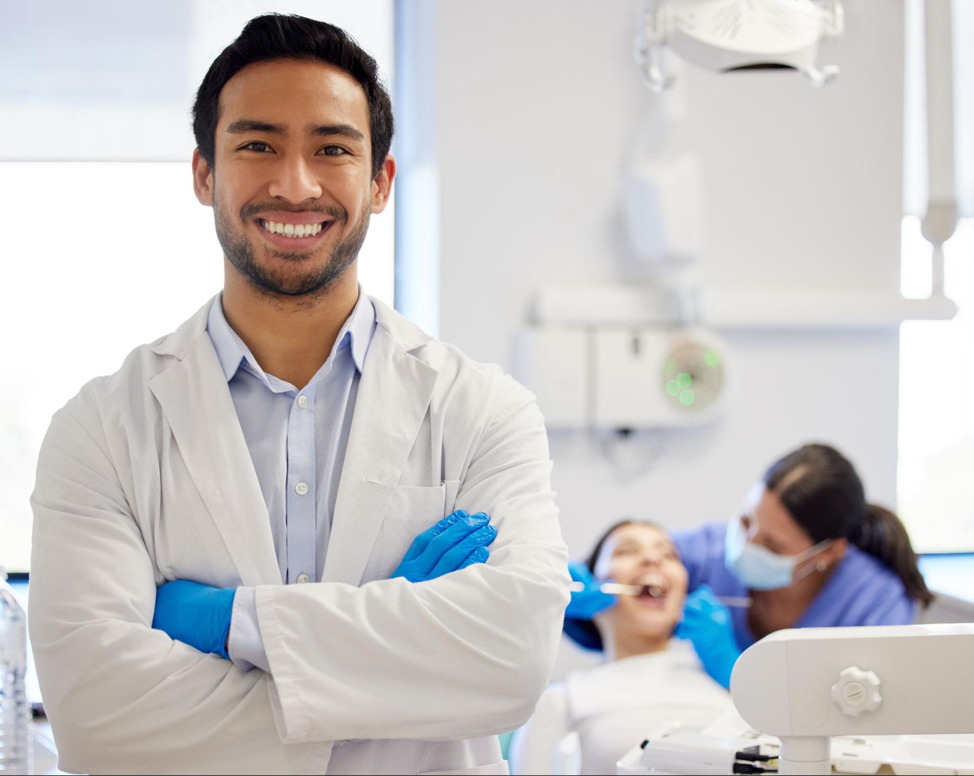 Male dentist smiling with a patient and a hygienist in the background.
