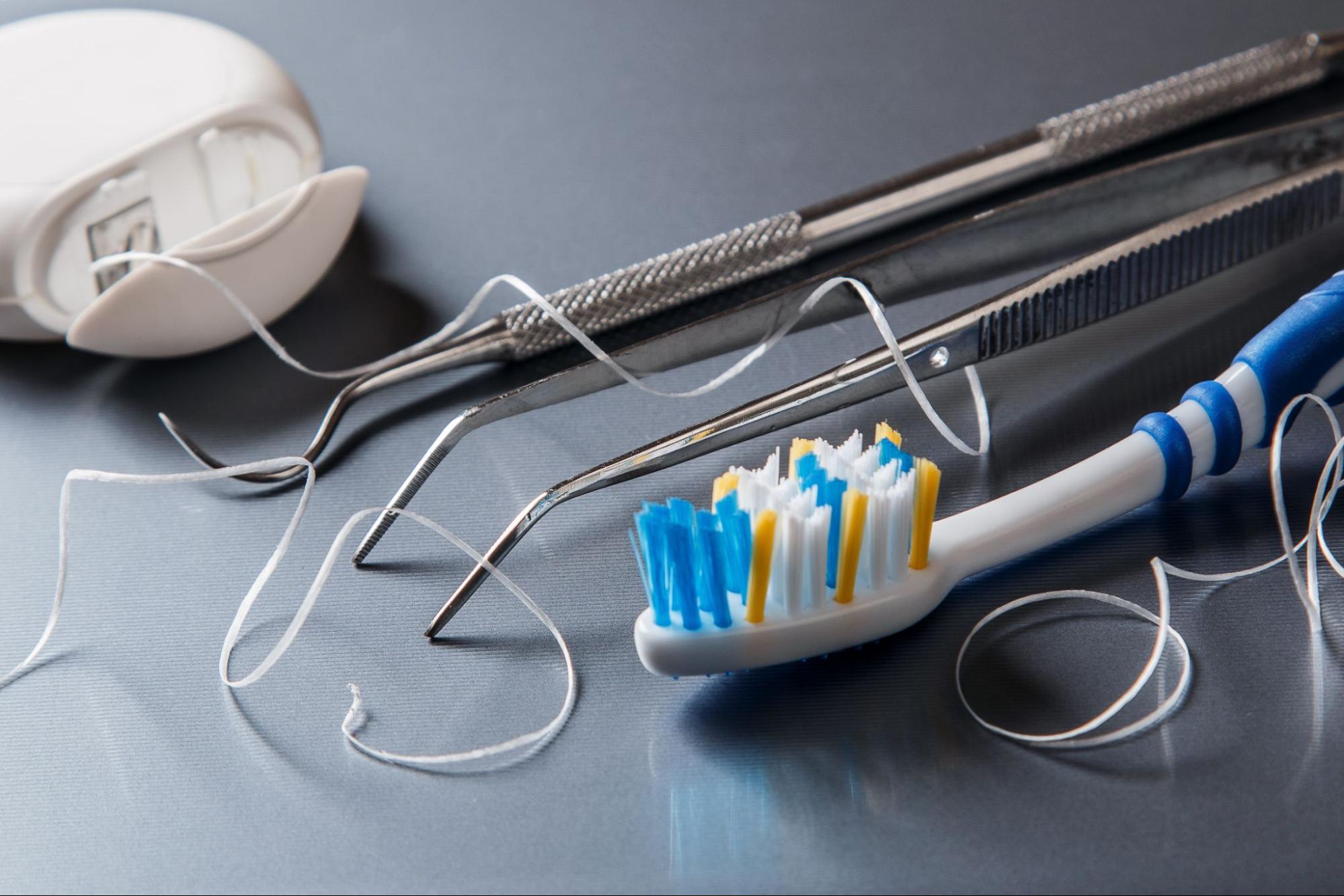 Various dental care tools, including dental floss, a toothbrush, and dental explorers used by dentists.