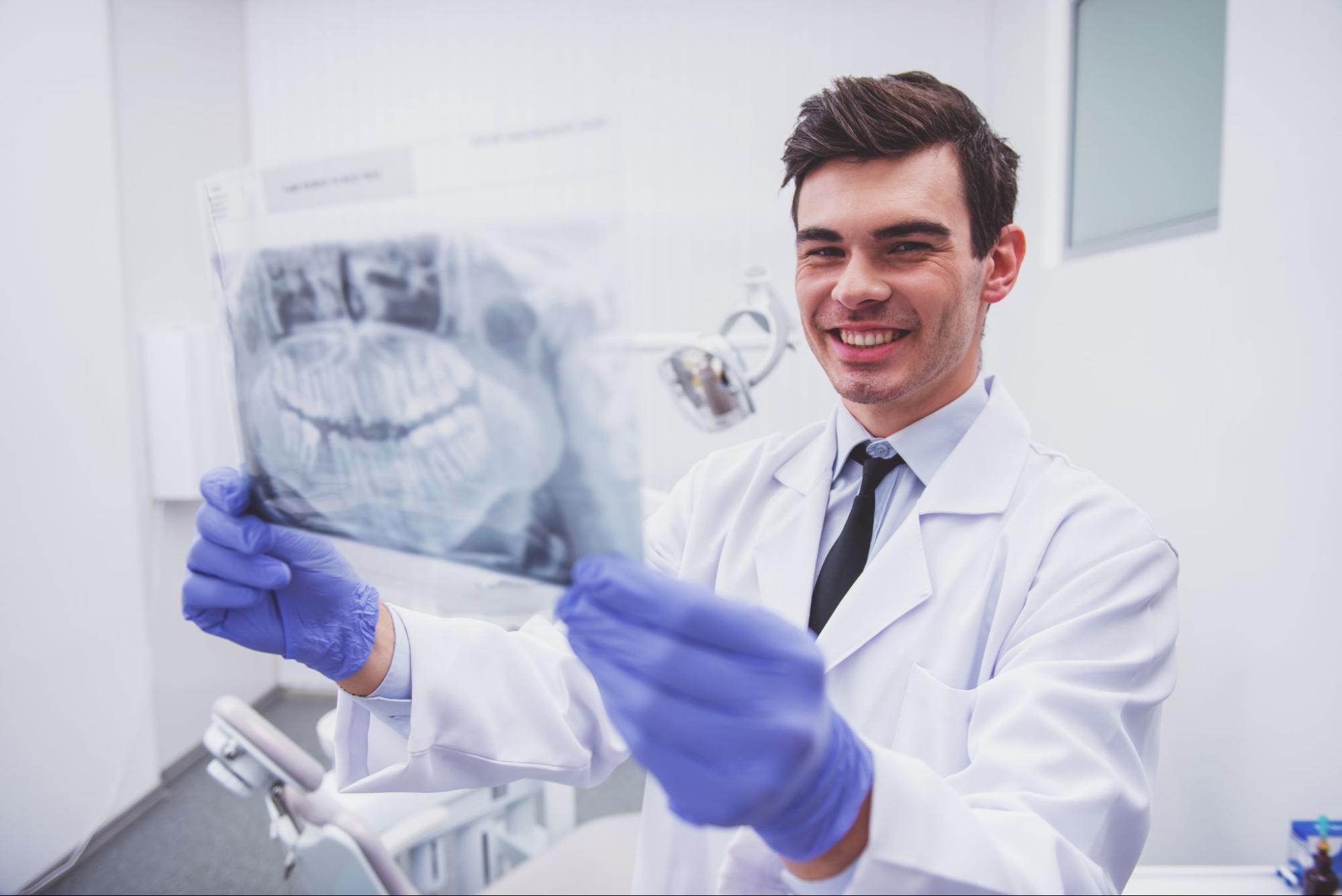 Smiling dentist holding an x-ray. 
