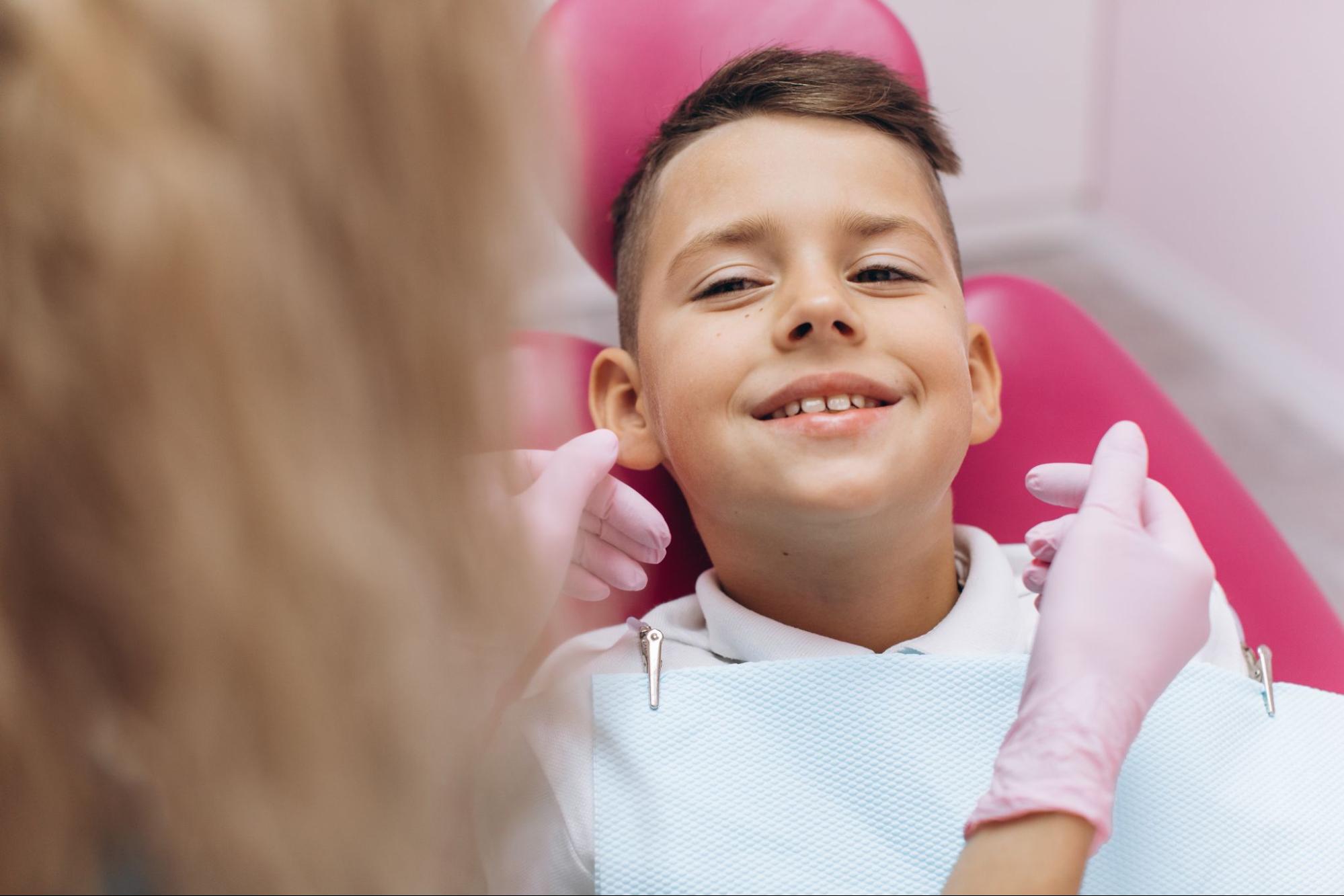 A young boy smiling at the dentist in an exam chair. 