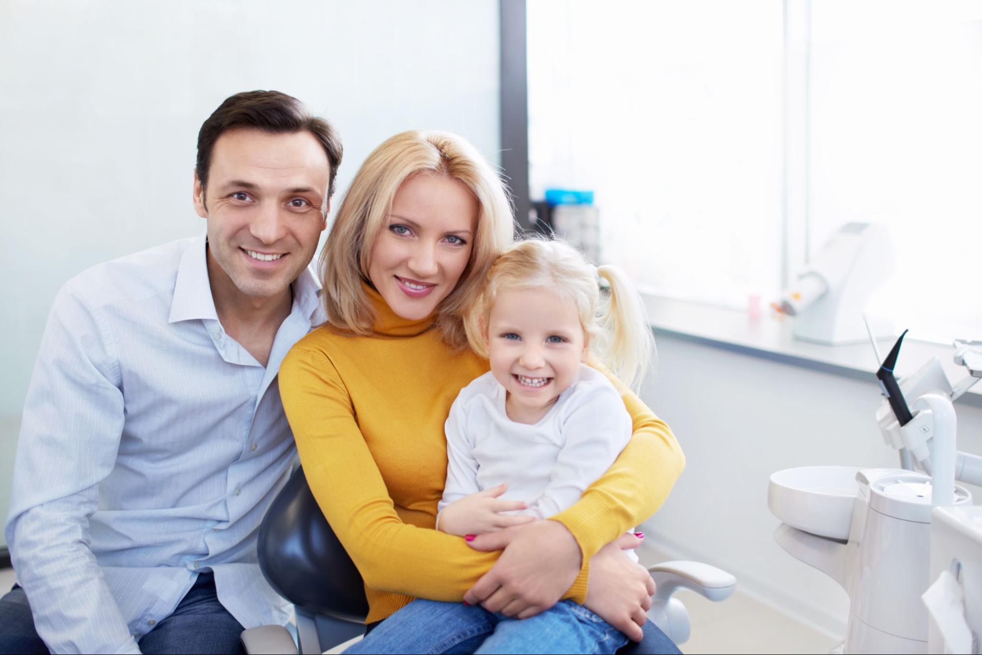 Smiling man, woman, and child at the dentist.