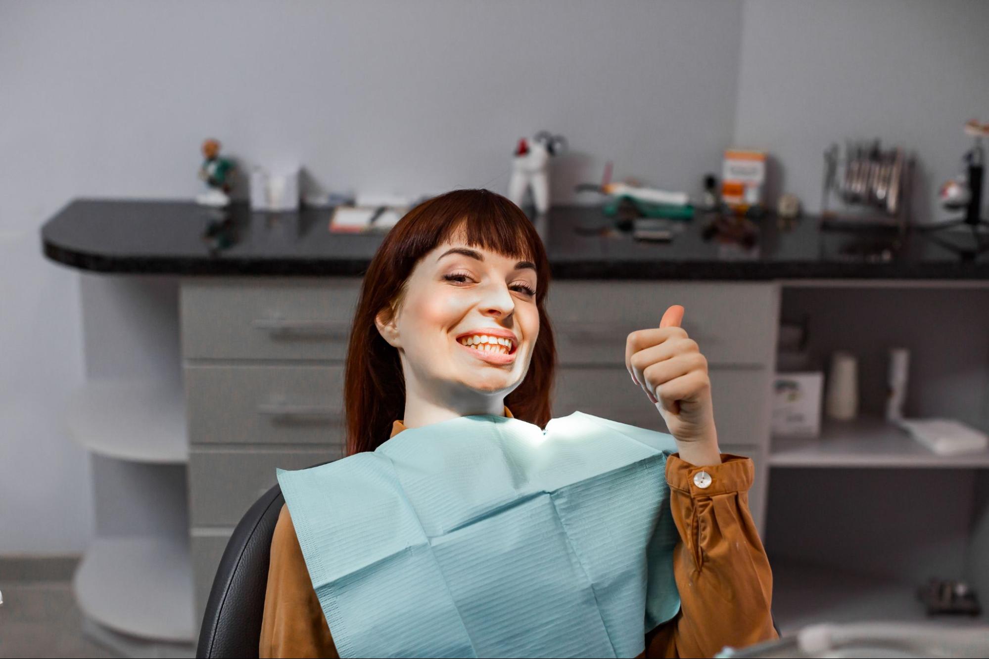 Woman smiling with a thumbs up while in an exam chair. 