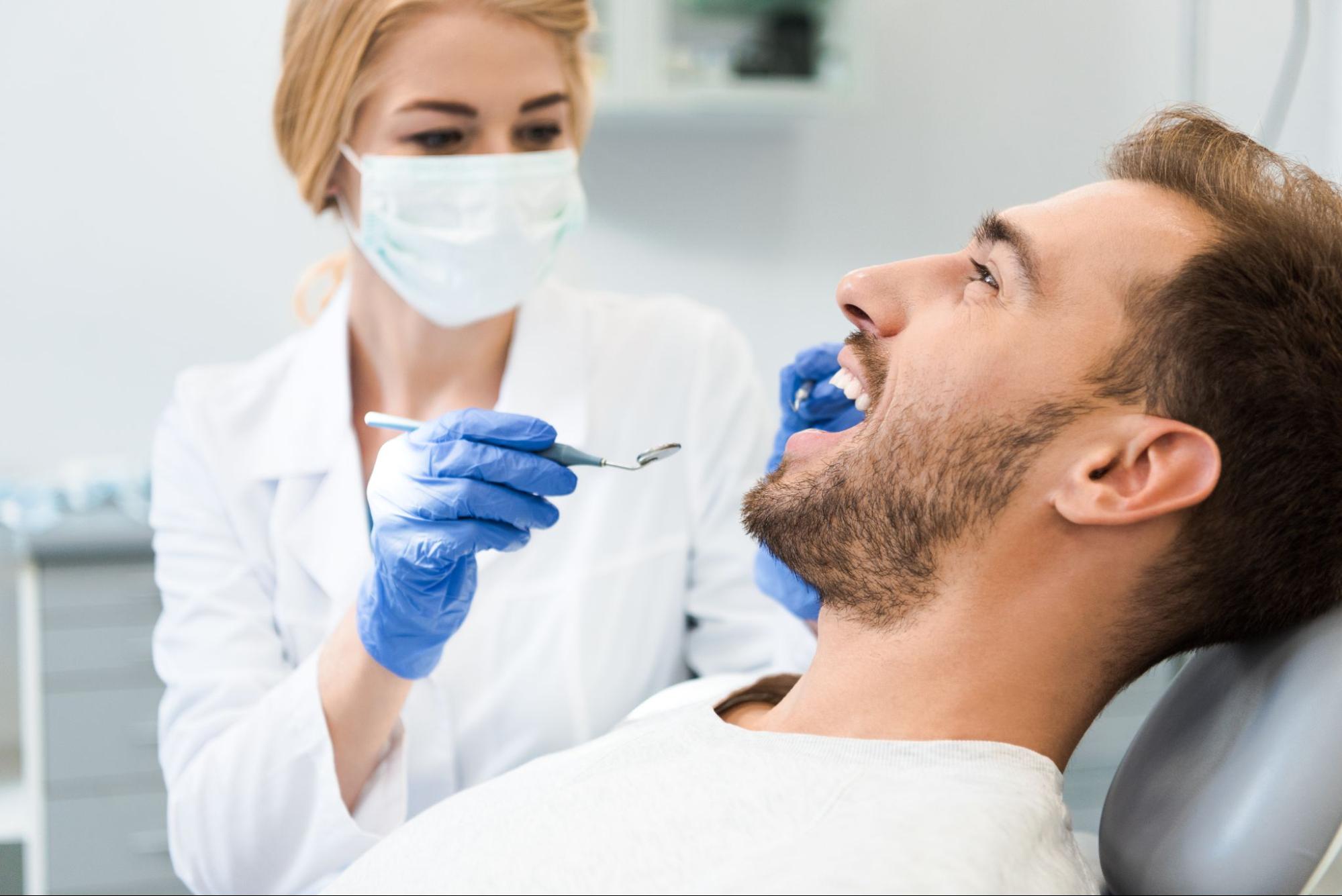 Man smiling at the dentist next to a female dentist. 
