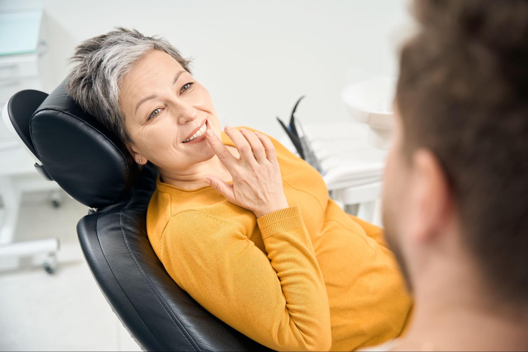A woman shows her dental implant to the dentist.