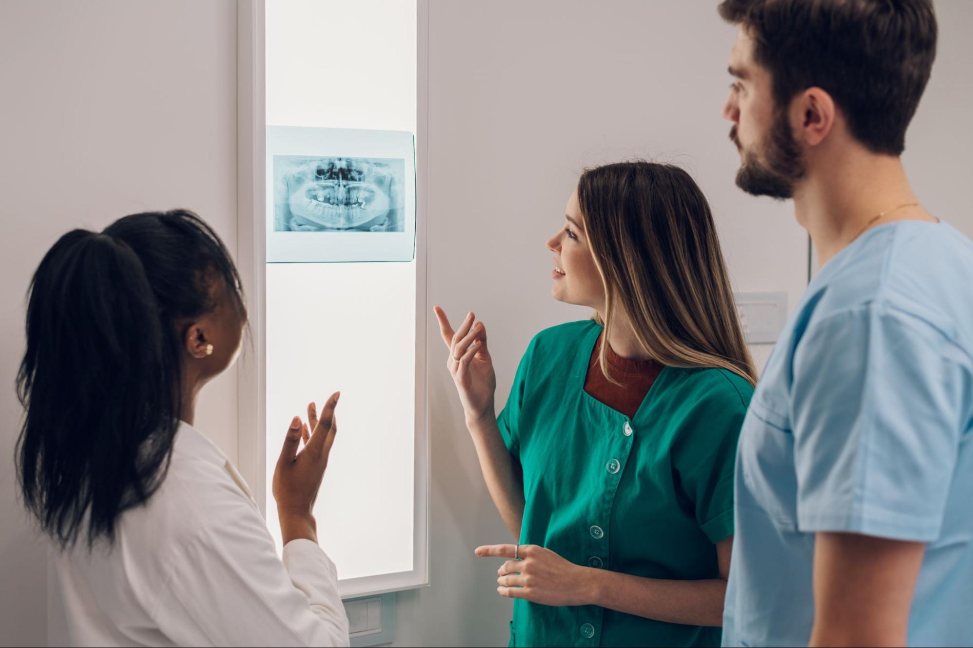 A group of dentists reviews a patient’s teeth X-ray.