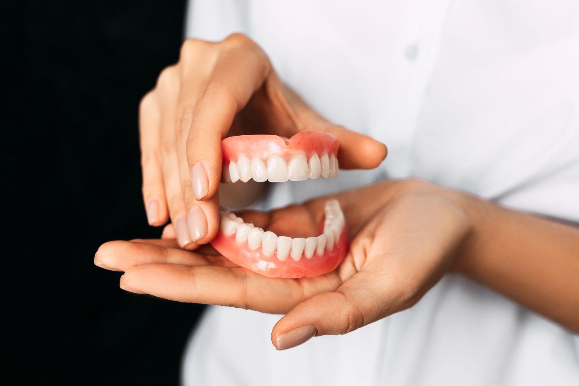 Close-up of a dentist presenting complete dentures in her hands.