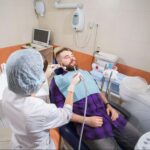 A dental hygienist cleaning a patient’s teeth before a dental checkup.
