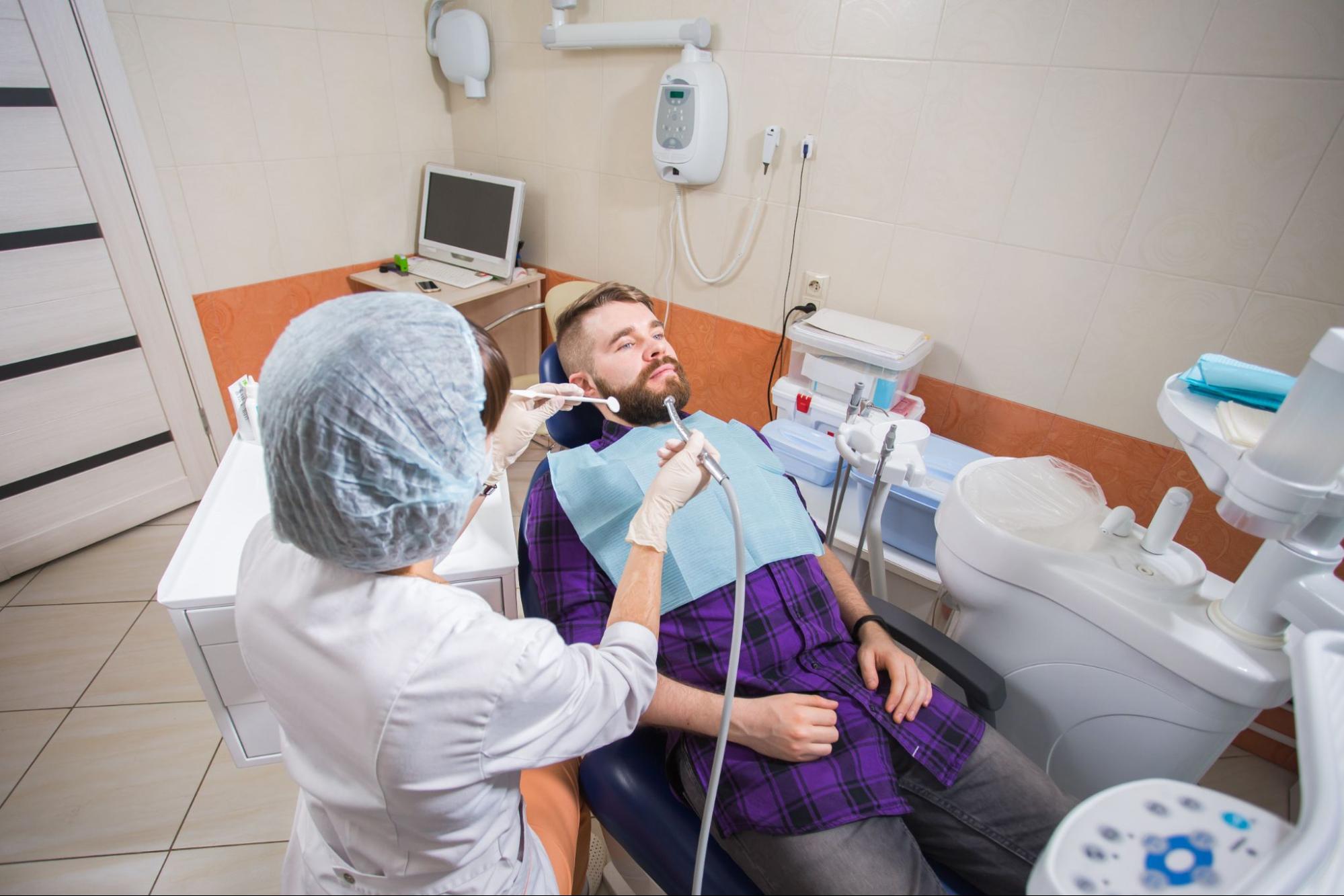 A dental hygienist cleaning a patient’s teeth before a dental checkup.