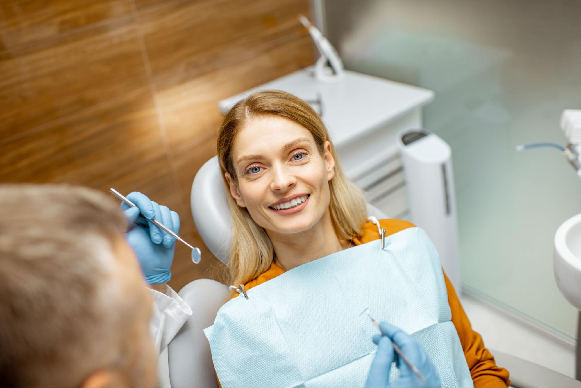 Woman smiling in a dental exam chair next to a dentist. 