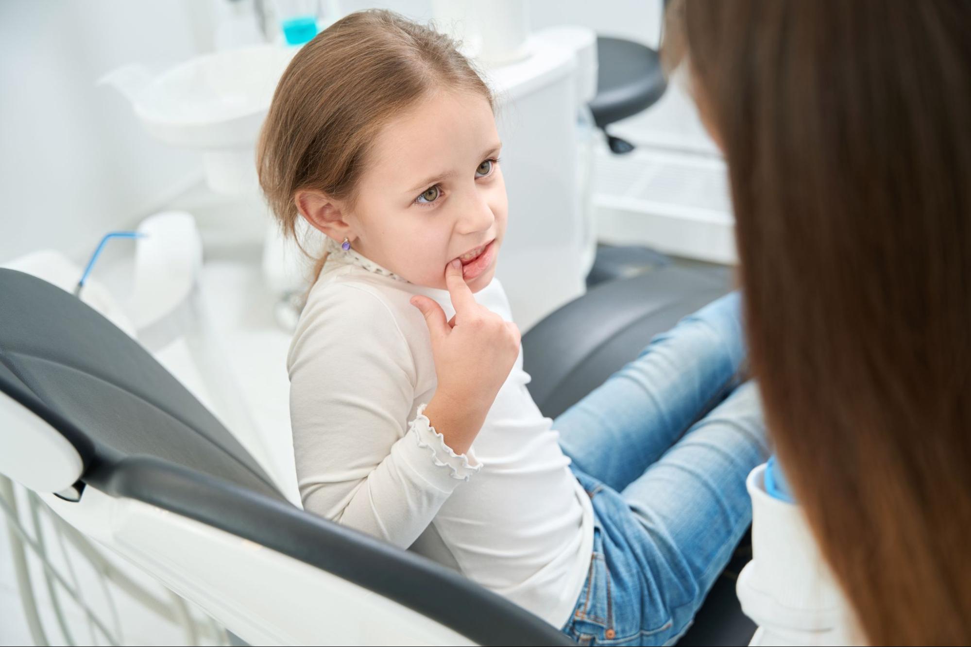 Young girl pointing towards her tooth.