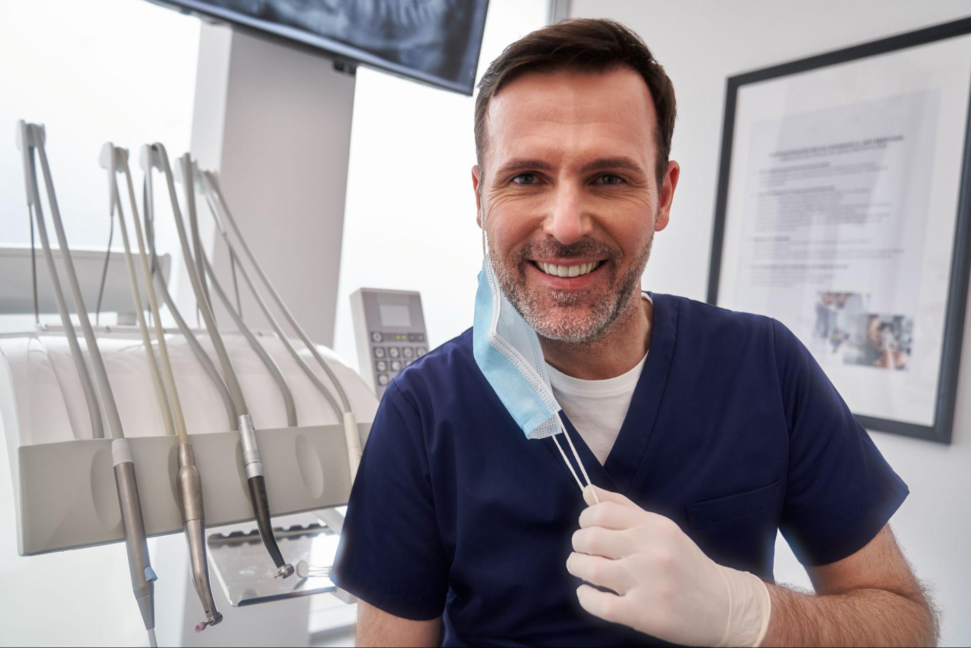 Smiling male dentist next to tools. 