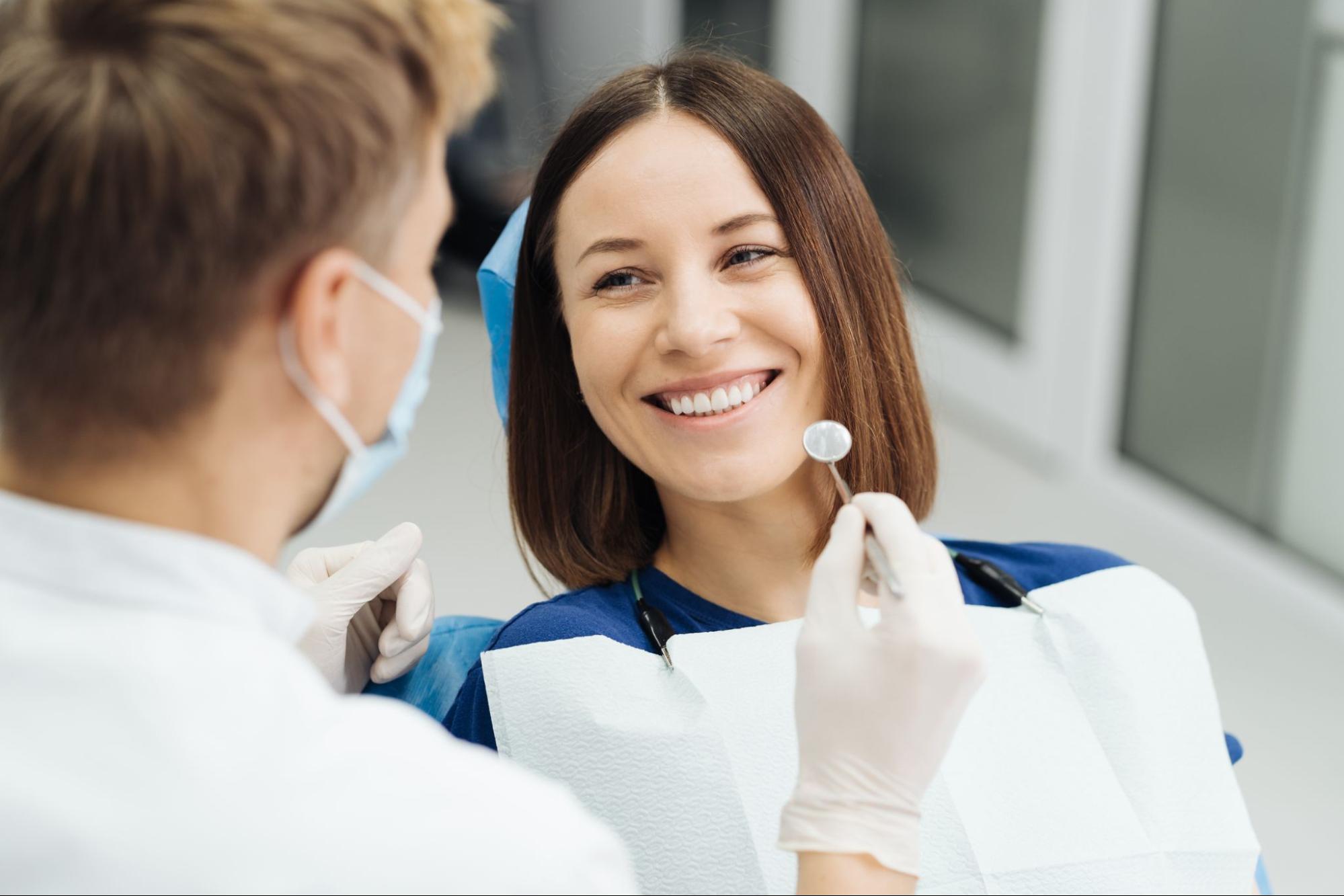 Woman smiling in a dental exam chair next to a dentist. 