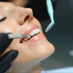 A close-up of a female patient's teeth during a dental crown preparation procedure.