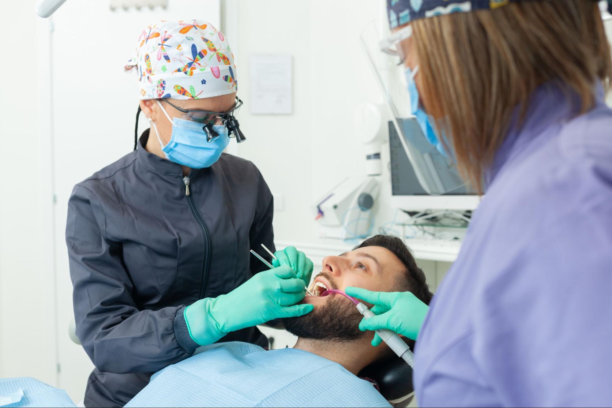 A dentist examining the patient's gums and teeth for signs of TMJ.  