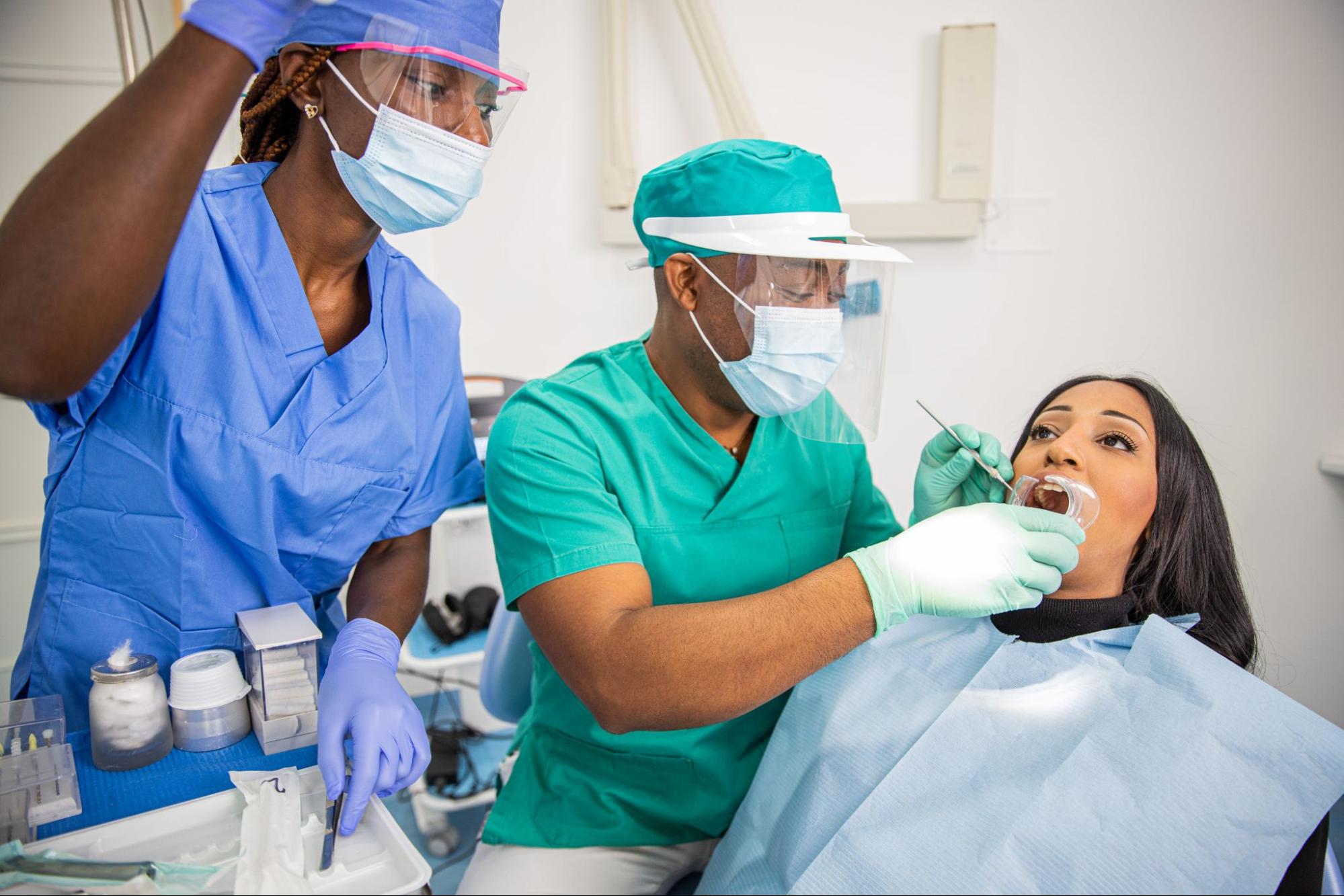 A dental exam performed by a male dentist with his assistant for periodontal disease.