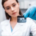 A female dentist examines a periapical teeth X-ray.