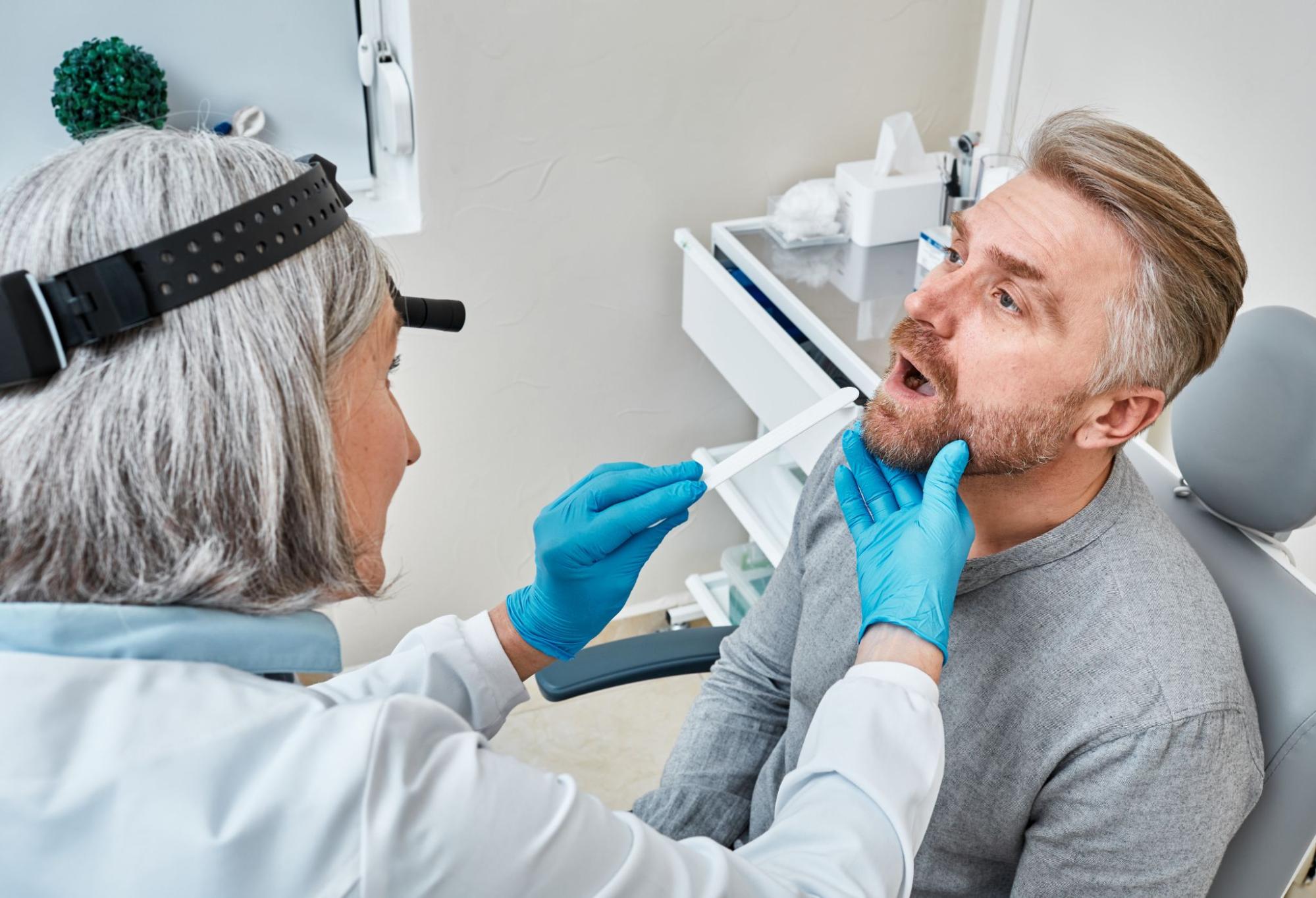 A female dental professional doing an oral exam on a man during a dental checkup.