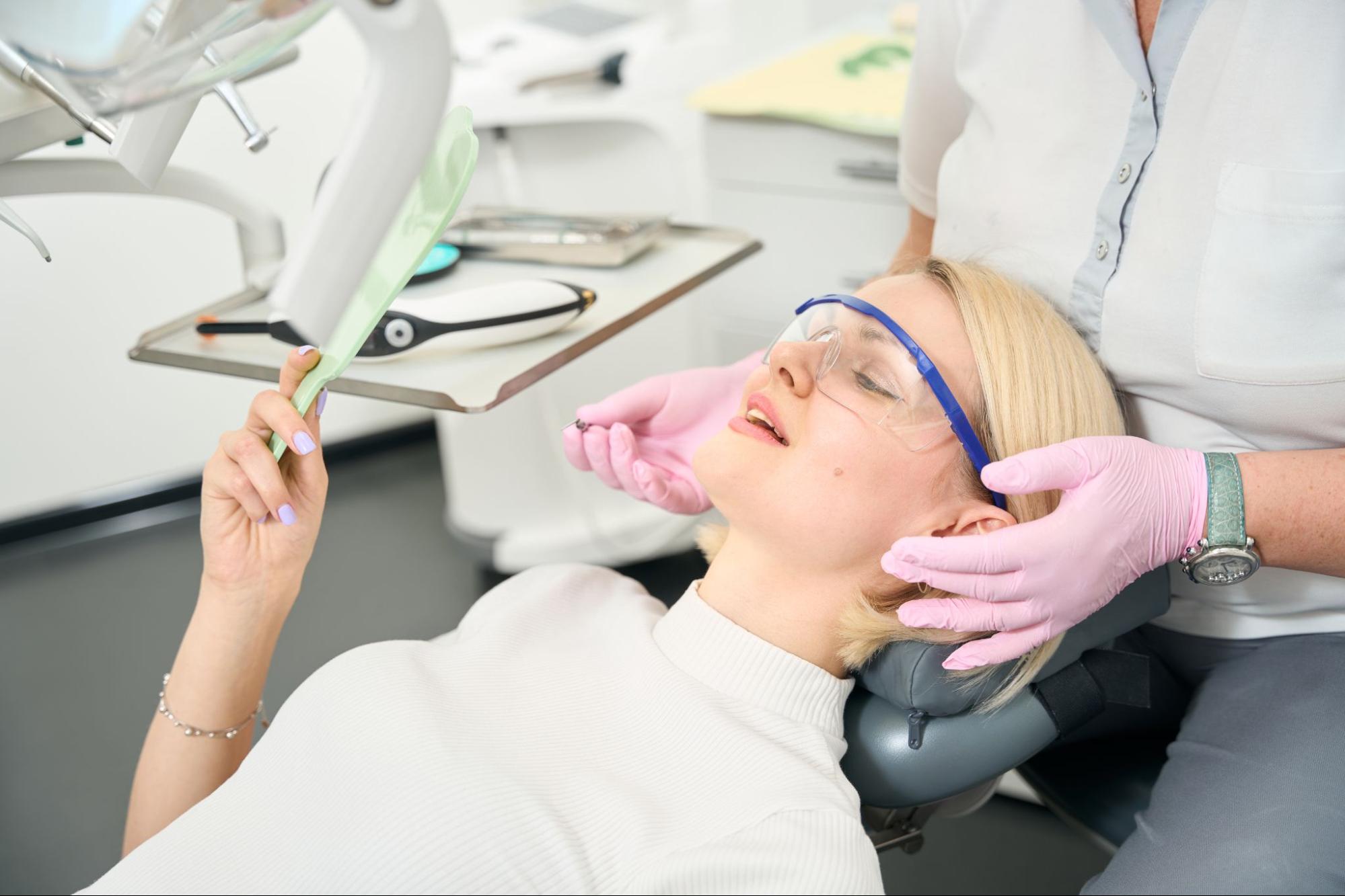 A woman looks at her restored tooth after receiving a dental crown.