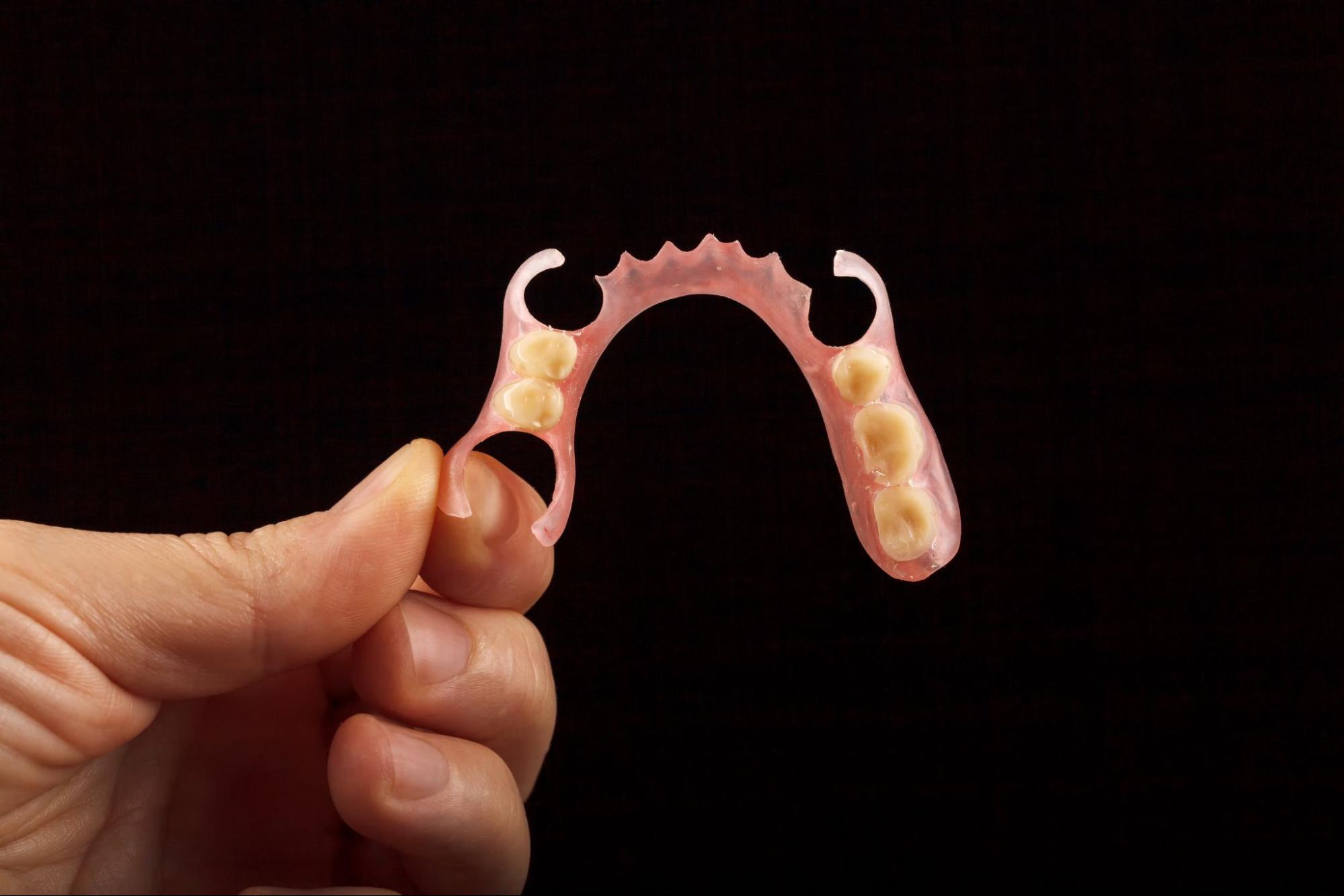 A partial denture held against a black background.