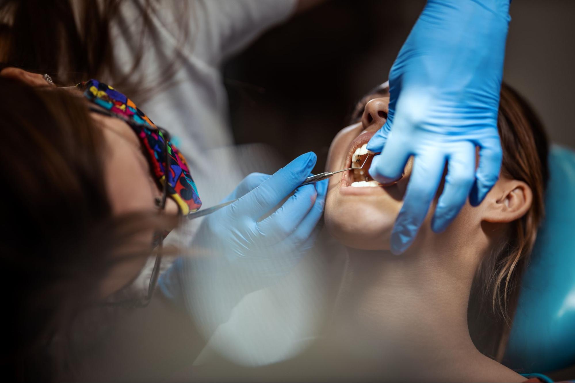 A dentist using a tool to check the back of a patient’s teeth during a dental checkup.