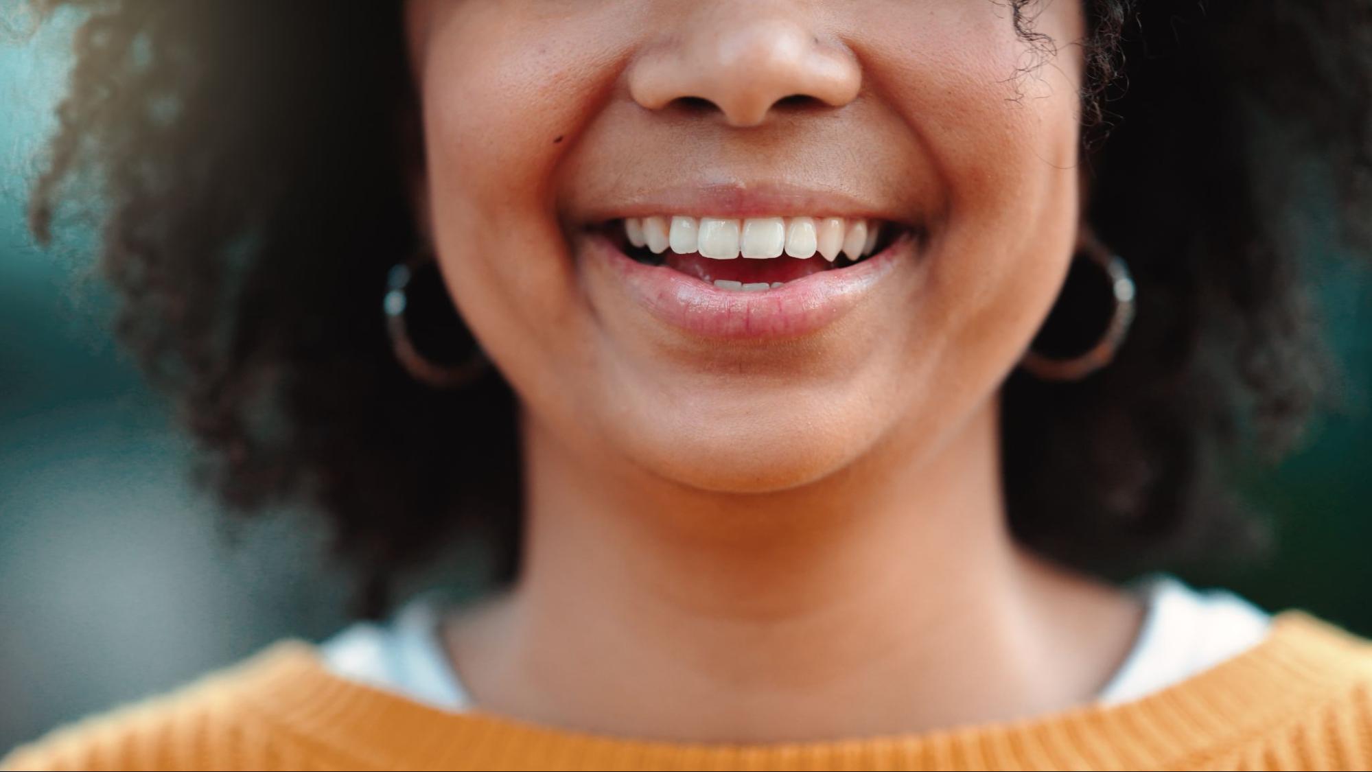 Woman smiling from the nose down to her shoulders. 