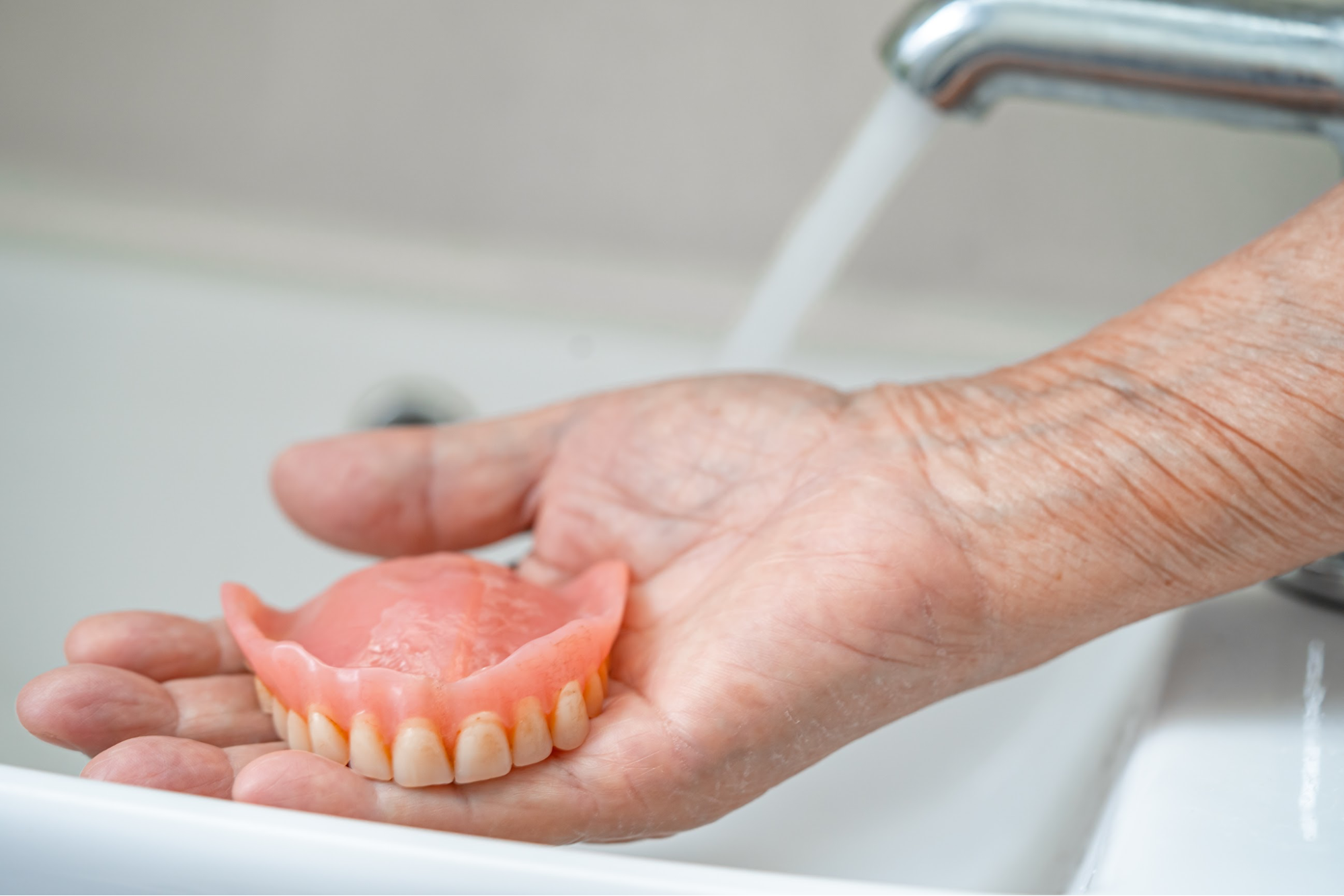 A hand holding a denture