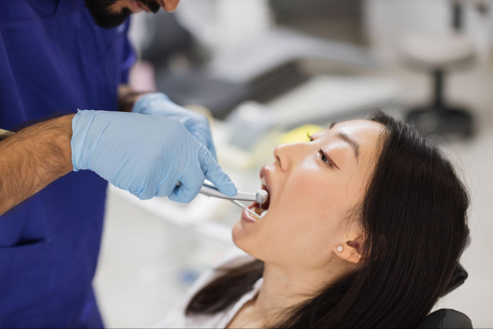 A male dentist checks a patient's teeth before undergoing teeth cleaning. 