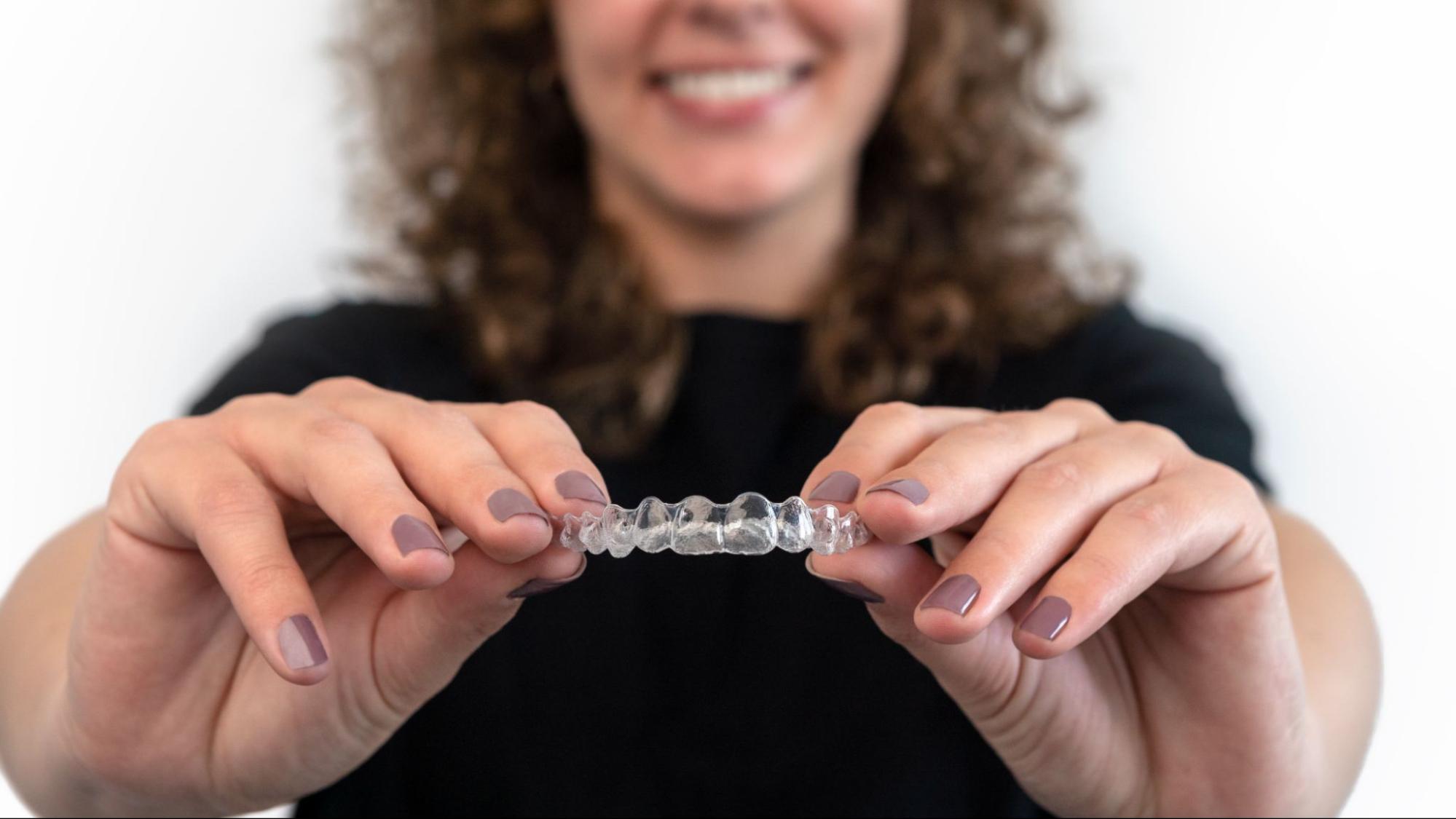 woman shows the Invisalign® aligner fit for upper teeth.