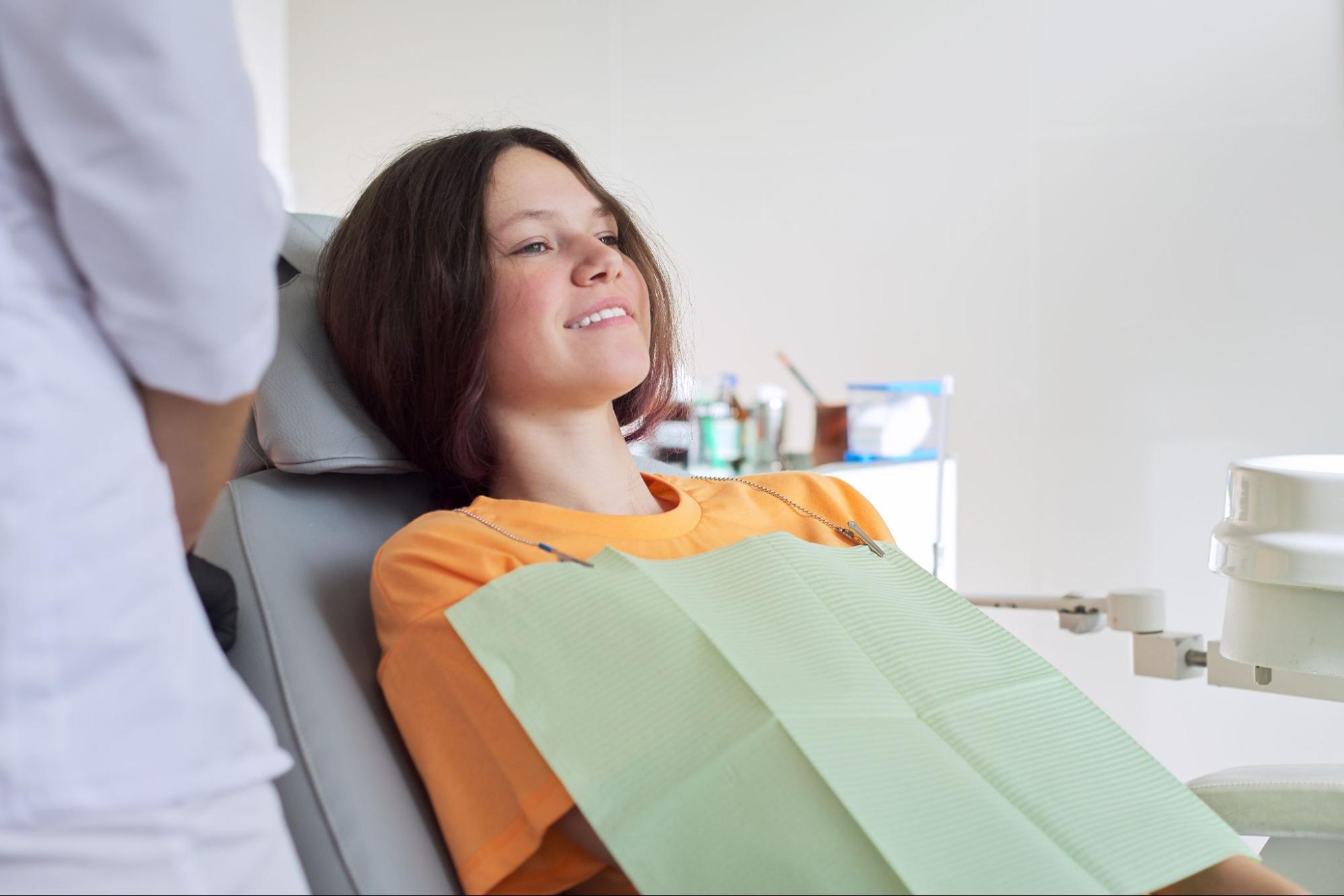 A teenage girl smiling in a dentist’s chair.