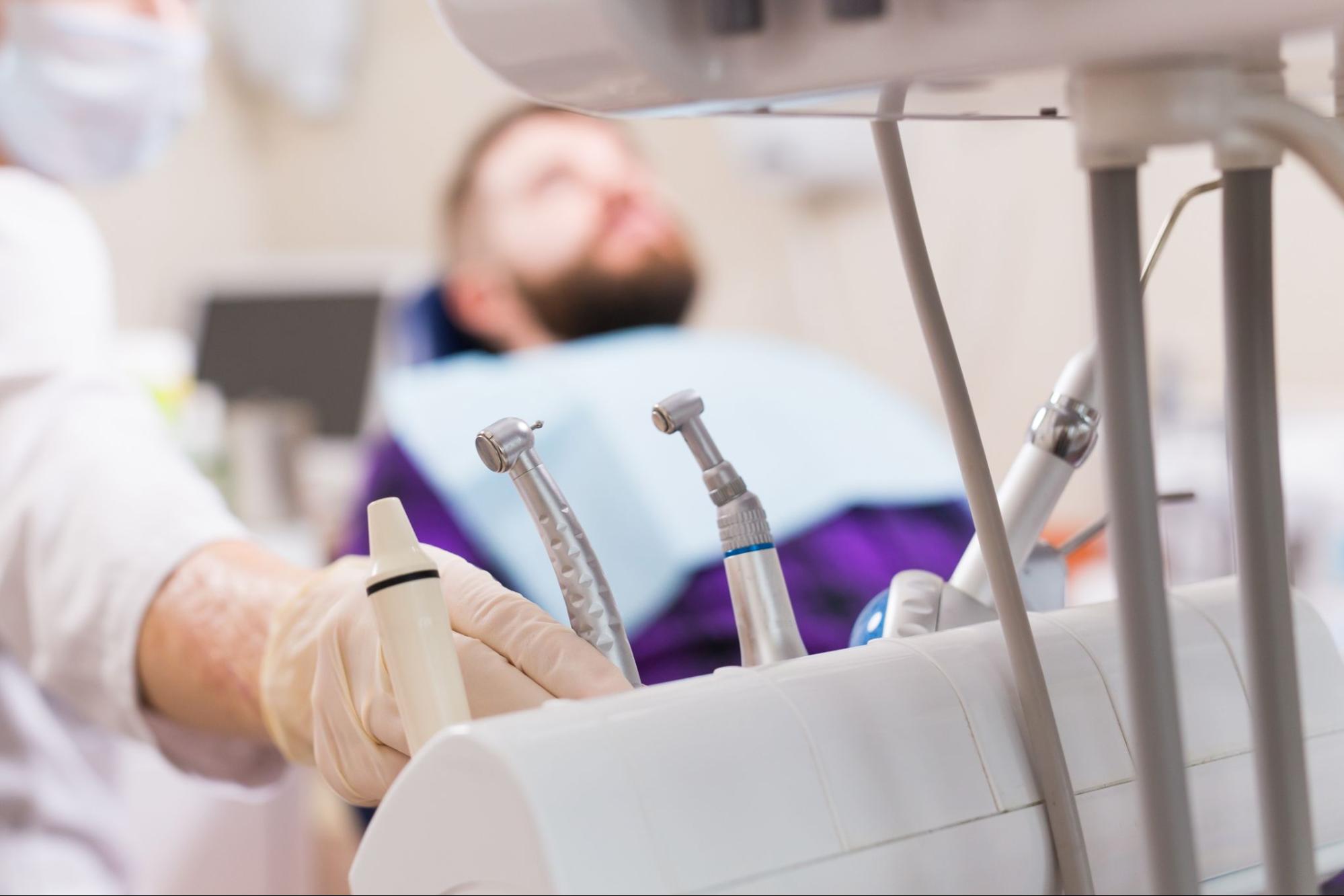 Man in a dental exam chair next to tools.