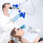 A dentist uses a dental microscope to examine a patient's mouth during a detailed checkup.
