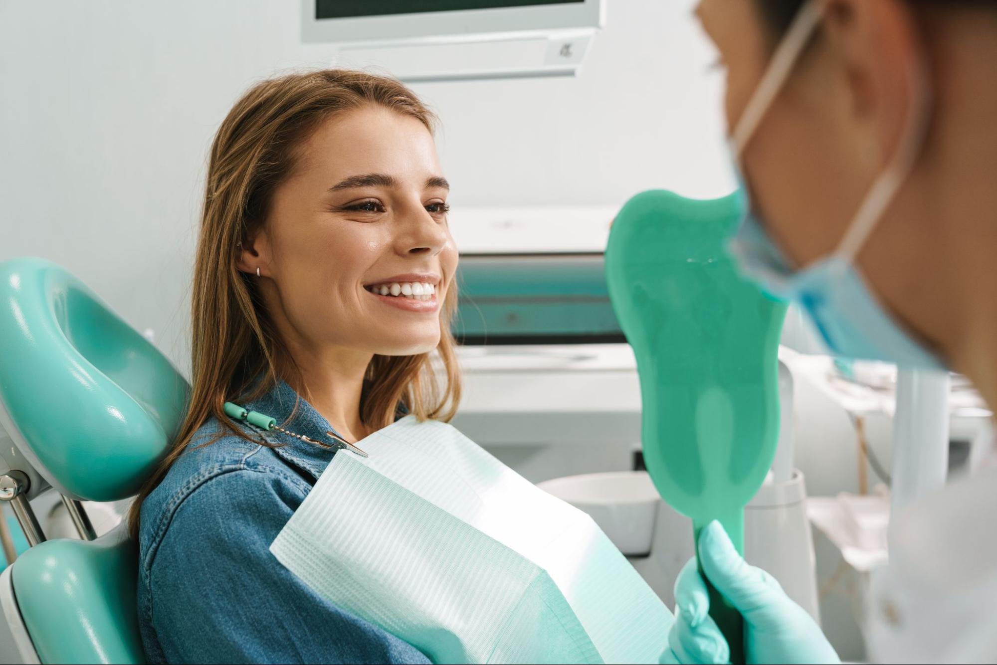 Woman smiling next to a dentist in a dental exam chair. 