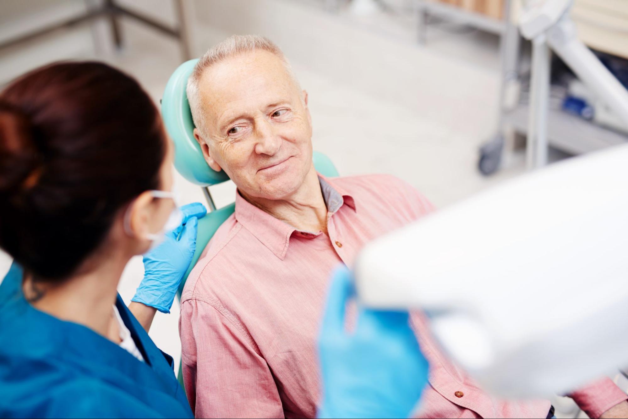 Older man smiling at a dentist in an exam chair.