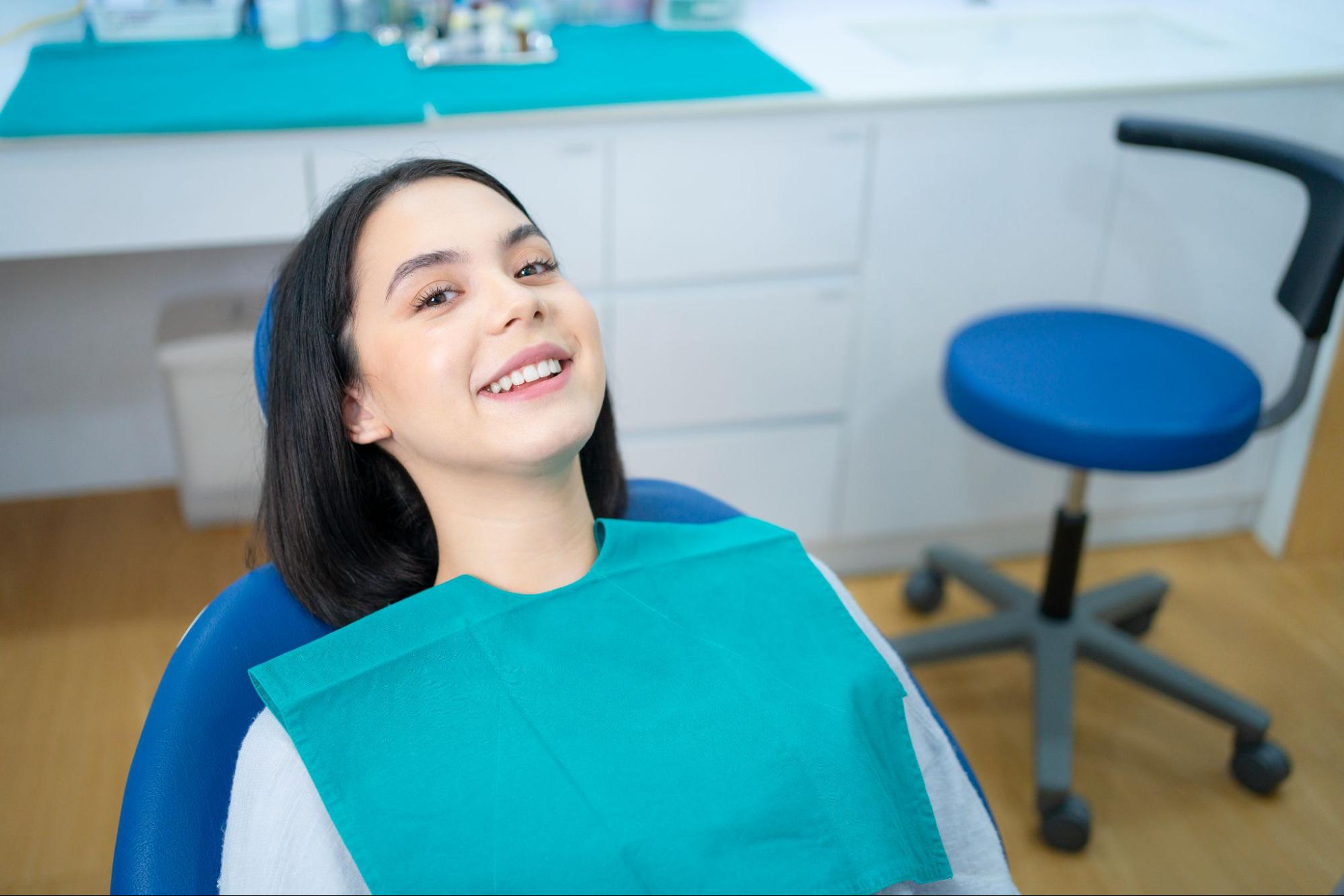 Young woman reclined in a dental exam chair and smiling. 