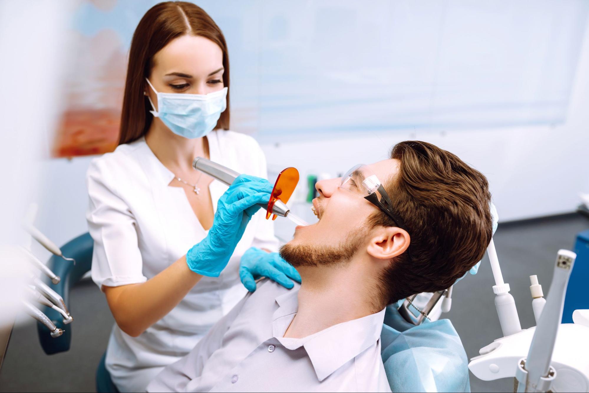 A young man sitting in the dentist's chair during a professional teeth cleaning procedure.